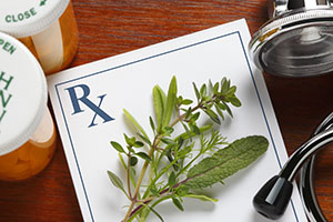 Fresh herbs on top of a doctor's prescription pad next to stethoscope